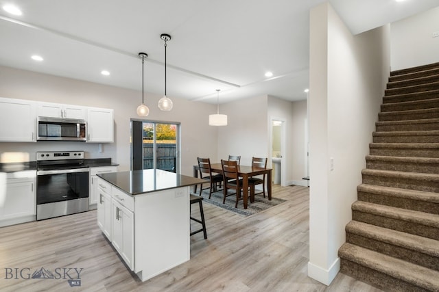 kitchen featuring a kitchen island, white cabinets, decorative light fixtures, appliances with stainless steel finishes, and light hardwood / wood-style floors