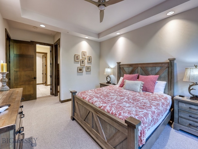 bedroom featuring light carpet, a raised ceiling, and ceiling fan