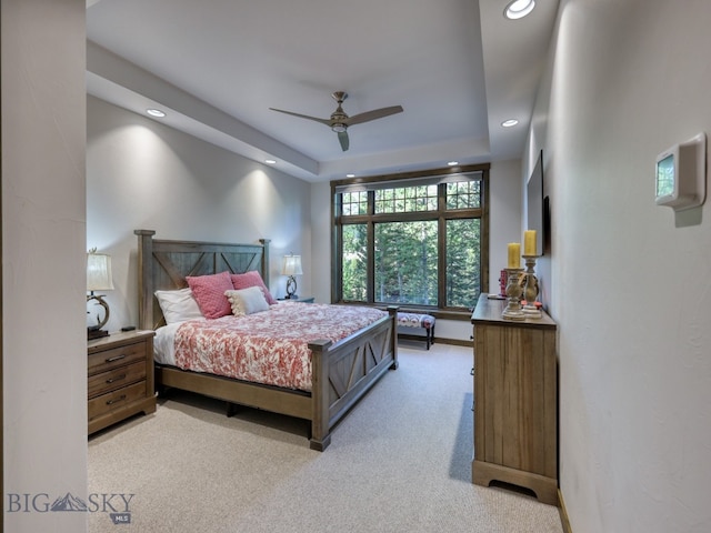 carpeted bedroom with a tray ceiling and ceiling fan