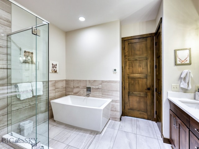 bathroom with tile walls, vanity, shower with separate bathtub, and tile patterned floors