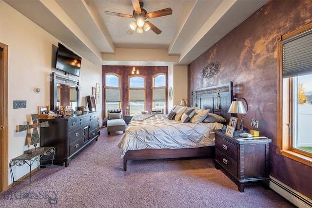 carpeted bedroom featuring a baseboard heating unit, multiple windows, a tray ceiling, and ceiling fan