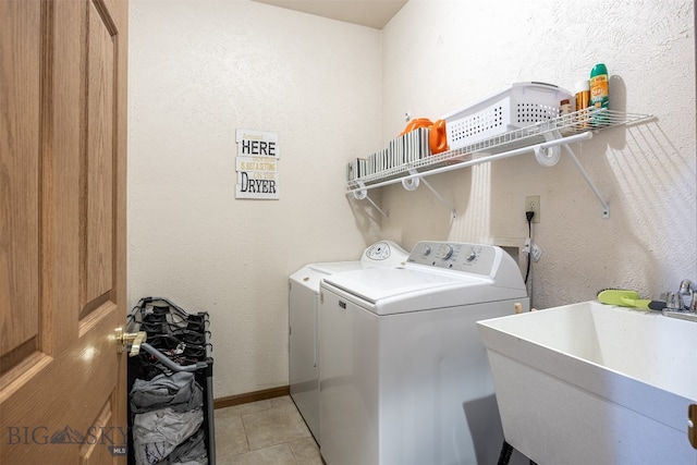 laundry area featuring light tile patterned flooring, independent washer and dryer, and sink