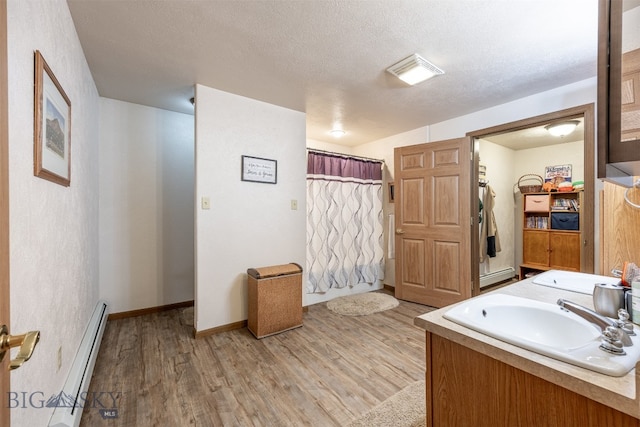 bathroom with vanity, hardwood / wood-style floors, a textured ceiling, and a baseboard radiator