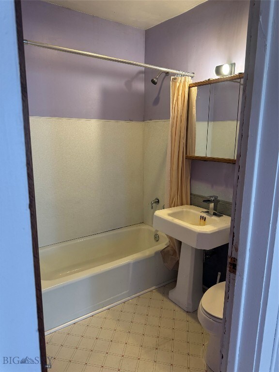 bathroom with shower / tub combo with curtain and toilet