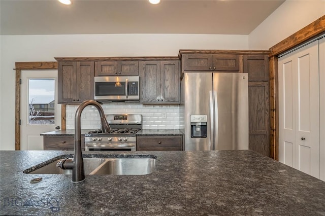 kitchen with dark brown cabinetry, sink, backsplash, and stainless steel appliances