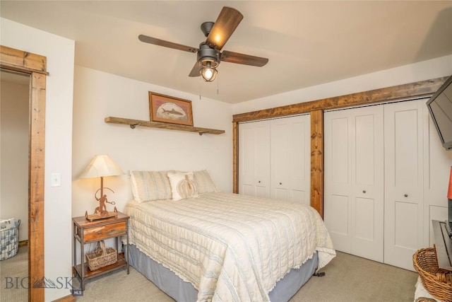 bedroom with light carpet, two closets, and ceiling fan