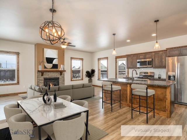 dining room featuring a stone fireplace, sink, and light hardwood / wood-style flooring