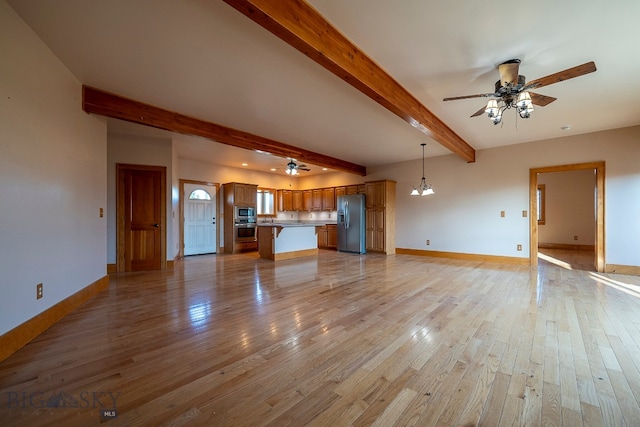 unfurnished living room featuring beam ceiling, light wood-type flooring, and ceiling fan with notable chandelier