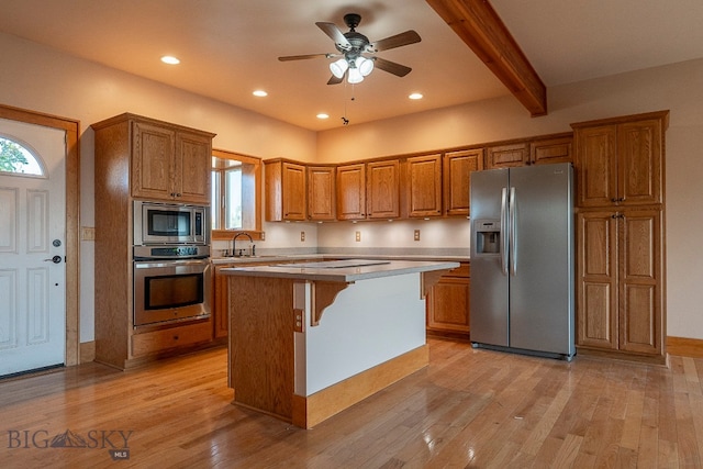 kitchen featuring appliances with stainless steel finishes, a kitchen island, ceiling fan, beam ceiling, and light hardwood / wood-style flooring