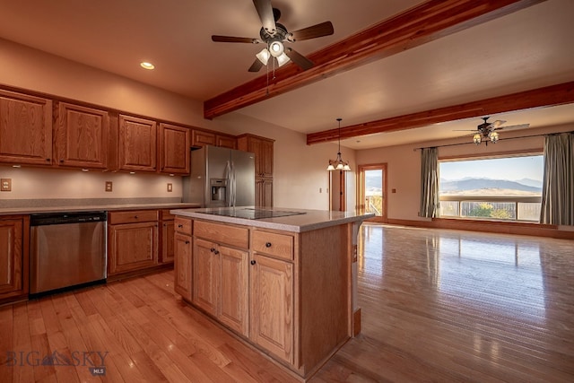 kitchen featuring beam ceiling, light hardwood / wood-style flooring, hanging light fixtures, a mountain view, and appliances with stainless steel finishes