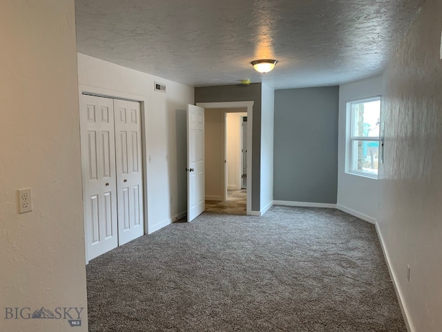 unfurnished bedroom featuring a closet, a textured ceiling, and carpet flooring