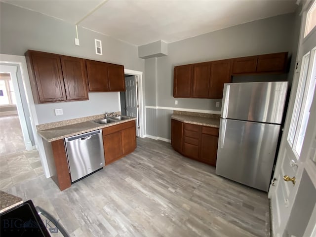 kitchen with light wood-type flooring, appliances with stainless steel finishes, and sink