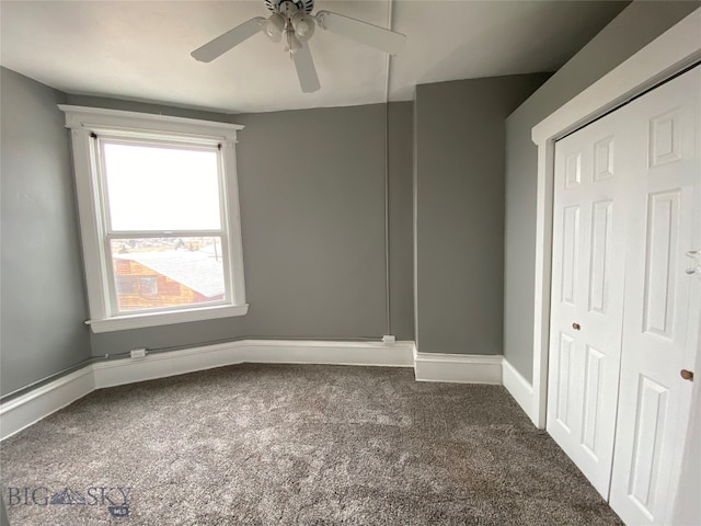 unfurnished room featuring ceiling fan and dark carpet