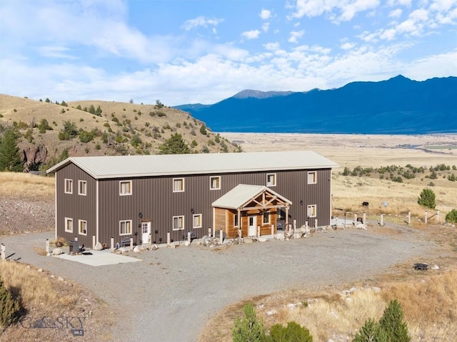 back of property with a mountain view and driveway