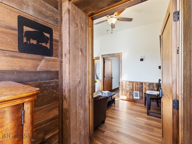 corridor featuring wainscoting, wood walls, and wood finished floors