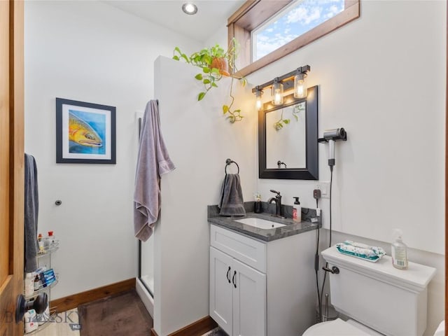 bathroom with vanity, toilet, baseboards, and recessed lighting