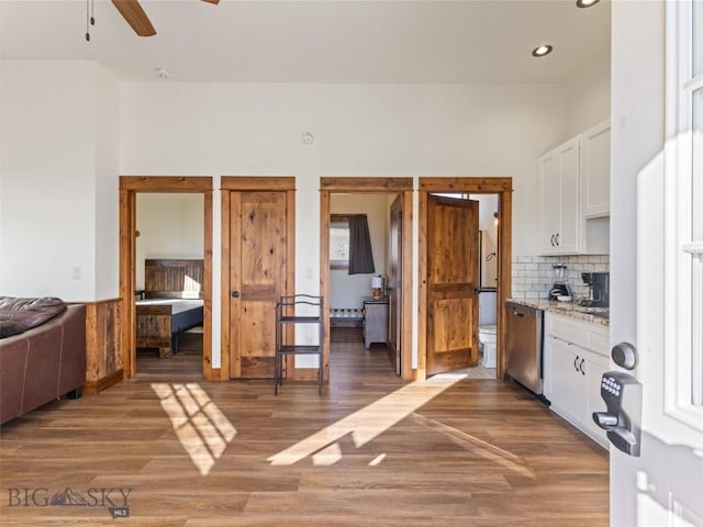 kitchen featuring light wood-type flooring, ceiling fan, backsplash, white cabinets, and stainless steel dishwasher