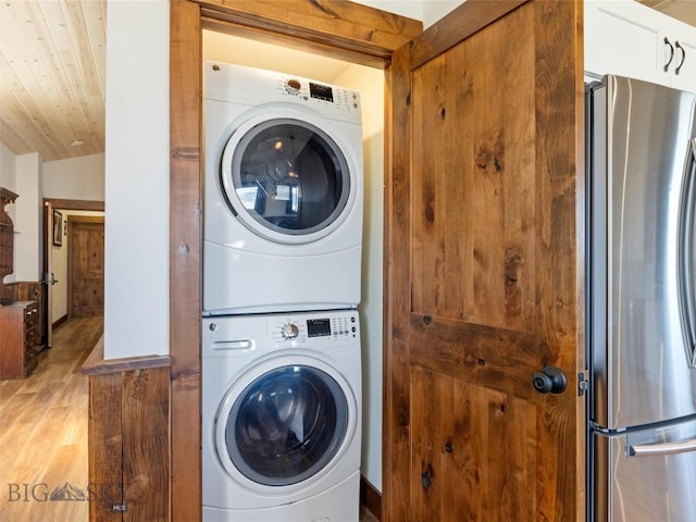 laundry area with stacked washer and clothes dryer, laundry area, and light wood finished floors