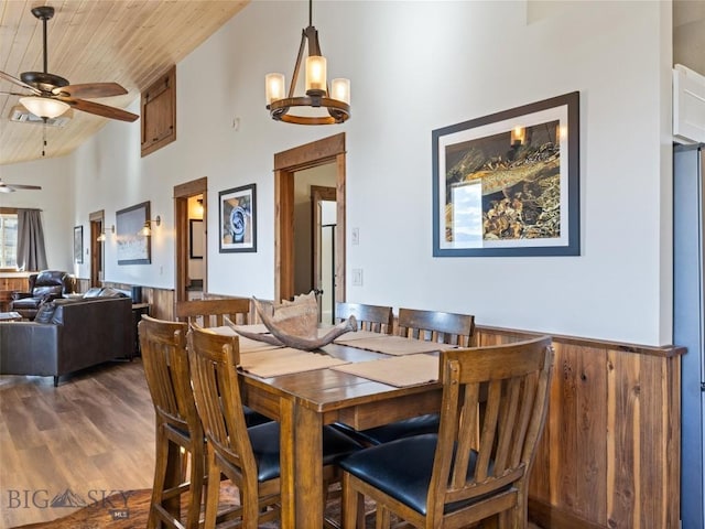 dining space featuring wooden ceiling, wood finished floors, ceiling fan with notable chandelier, and high vaulted ceiling