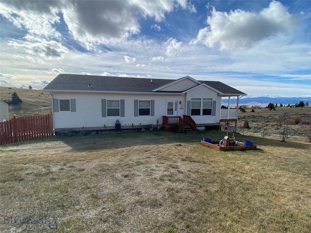 rear view of house featuring a mountain view and a lawn