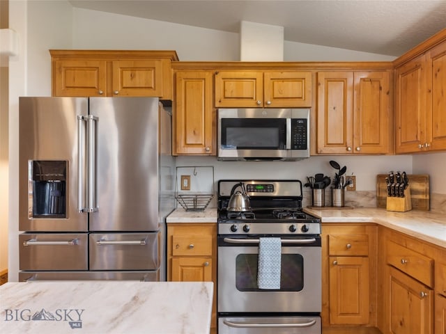 kitchen featuring appliances with stainless steel finishes and lofted ceiling