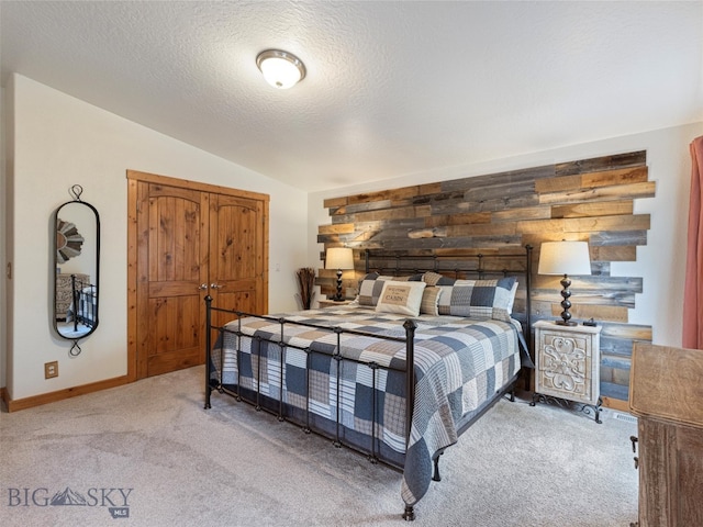 bedroom with light carpet, a textured ceiling, and vaulted ceiling