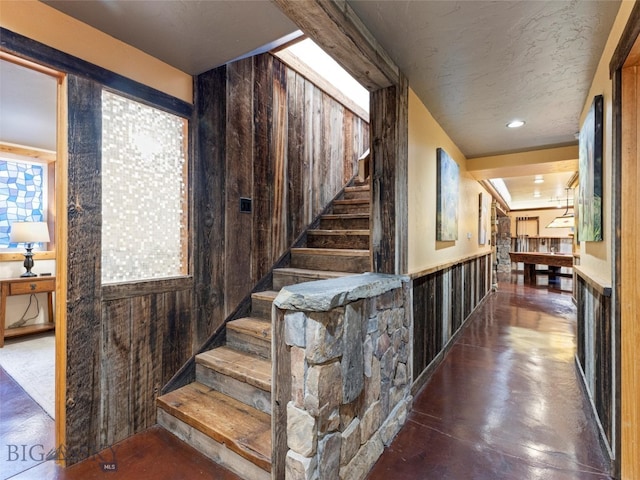 staircase featuring wood walls and a textured ceiling