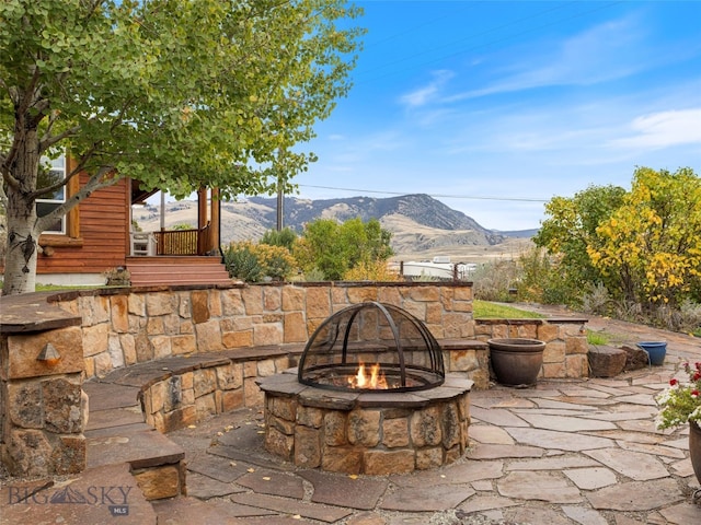 view of patio with an outdoor fire pit and a mountain view