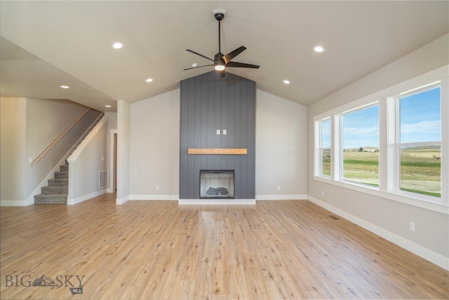 unfurnished living room with vaulted ceiling, a large fireplace, ceiling fan, and light hardwood / wood-style flooring