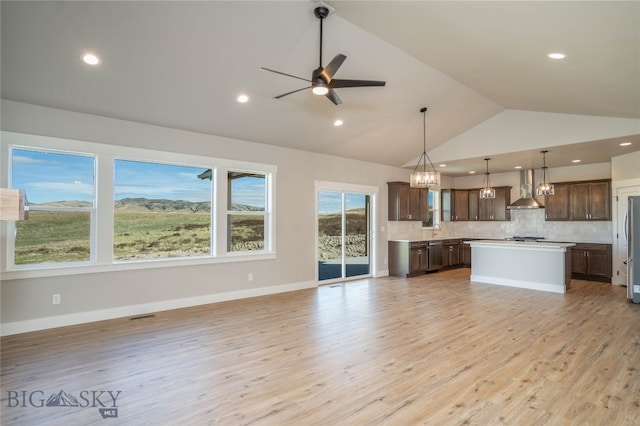 kitchen featuring a kitchen island, pendant lighting, tasteful backsplash, ceiling fan, and wall chimney exhaust hood