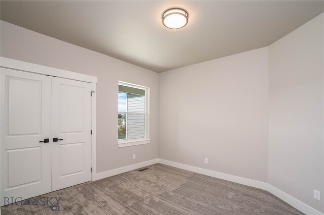 unfurnished bedroom with light carpet and a closet