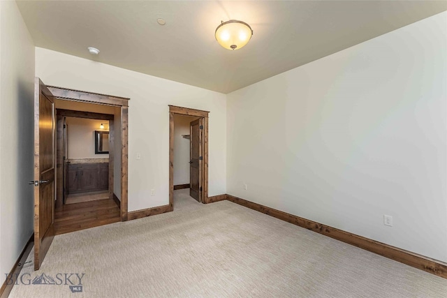 unfurnished bedroom featuring connected bathroom and light colored carpet