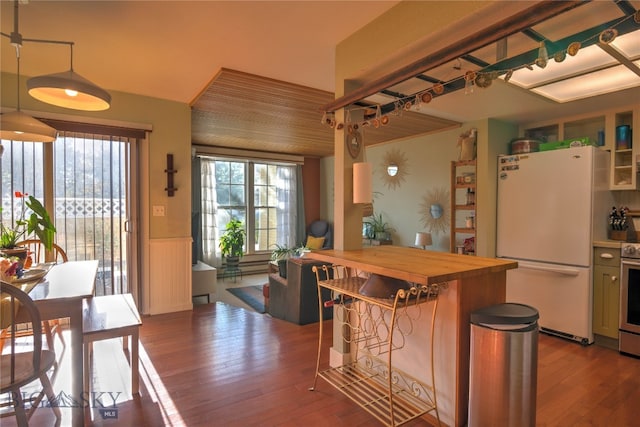 kitchen featuring wood-type flooring, butcher block counters, a kitchen breakfast bar, pendant lighting, and white fridge