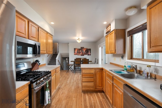 kitchen with light hardwood / wood-style flooring, stainless steel appliances, sink, and kitchen peninsula