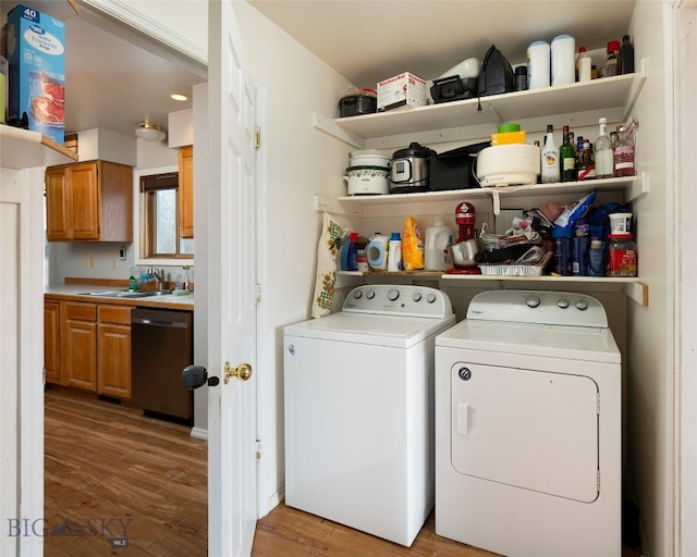 laundry area featuring light hardwood / wood-style floors, sink, and washing machine and clothes dryer