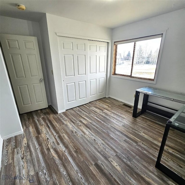 97 Ghost Canyon Ct, Belgrade, MT 59714 - unfurnished bedroom featuring dark wood-style floors, baseboards, visible vents, and a closet