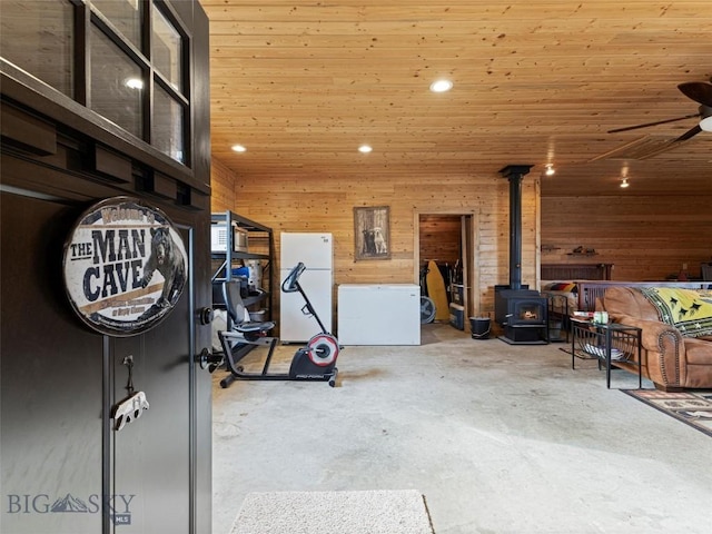 193 Tobe Rd, Ennis, MT 59729 - garage with freestanding refrigerator, a wood stove, a ceiling fan, wooden walls, and recessed lighting