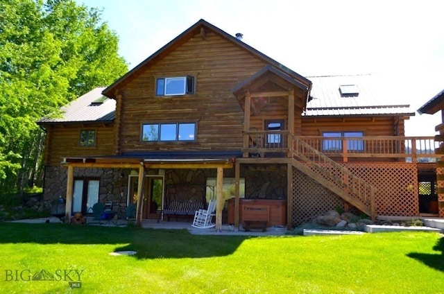 155 Moose Run, Polaris, MT 59746 - rear view of property with a hot tub, a patio area, stone siding, and a lawn