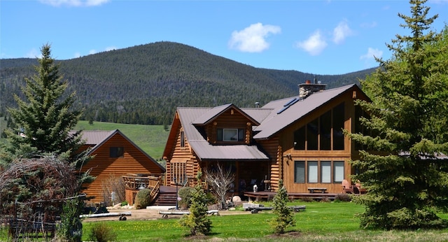 back of house featuring a mountain view and a yard