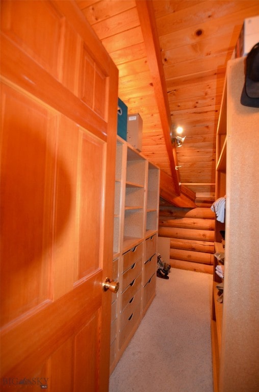 spacious closet with vaulted ceiling with beams and light colored carpet