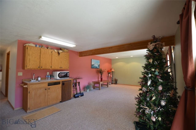 kitchen featuring beamed ceiling, sink, and light colored carpet