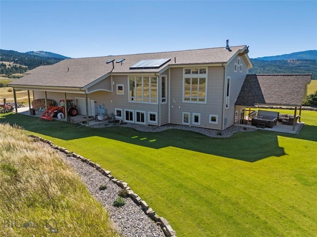 back of house with a patio, a mountain view, and a lawn