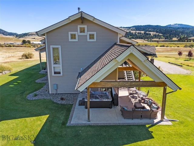 back of house featuring a patio, a mountain view, and a lawn