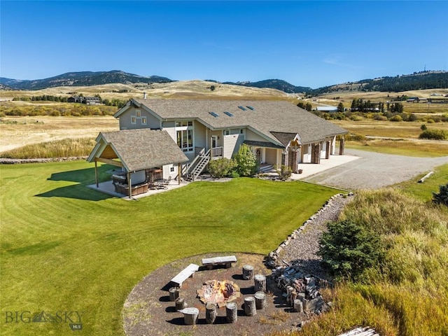 exterior space featuring a garage, a mountain view, a front yard, and a patio area