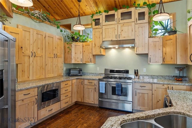 kitchen with stainless steel appliances, light stone countertops, light brown cabinets, and hanging light fixtures