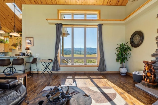 living room featuring a skylight, a high ceiling, wood ceiling, a mountain view, and dark wood-type flooring