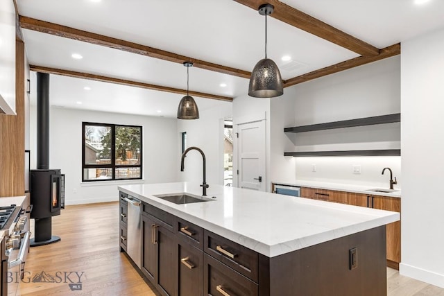 kitchen with sink, pendant lighting, appliances with stainless steel finishes, and an island with sink