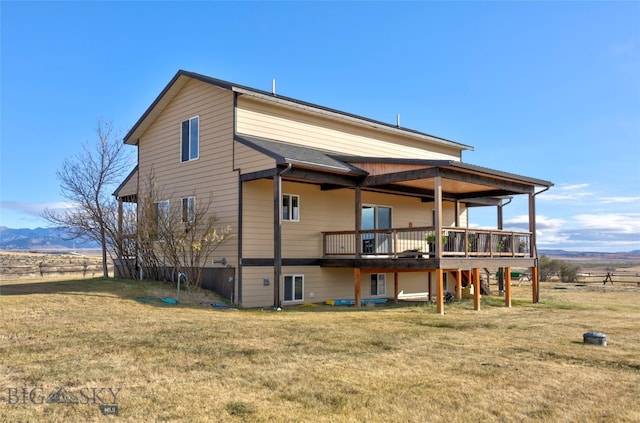 back of house with a lawn and a deck with mountain view