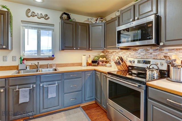 kitchen featuring appliances with stainless steel finishes, hardwood / wood-style floors, tasteful backsplash, and sink