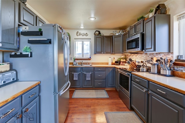 kitchen with dark wood-type flooring, stainless steel appliances, tasteful backsplash, and sink